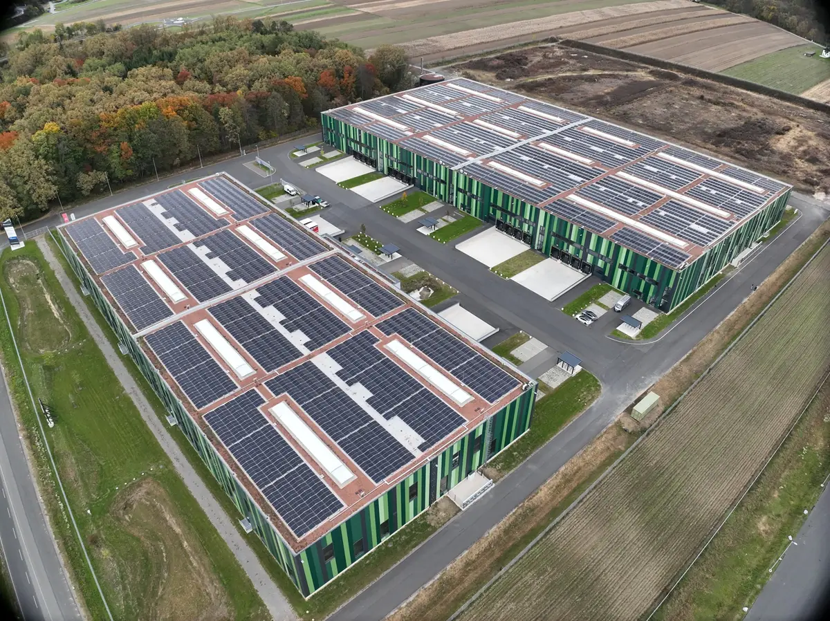 Luftaufnahme zweier Logistikhallen mit großflächigen Aufdach-Photovoltaikanlagen